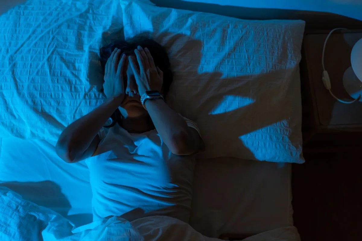 Pessoa com insônia deitada na cama de madrugada, retrato do sono prejudicado