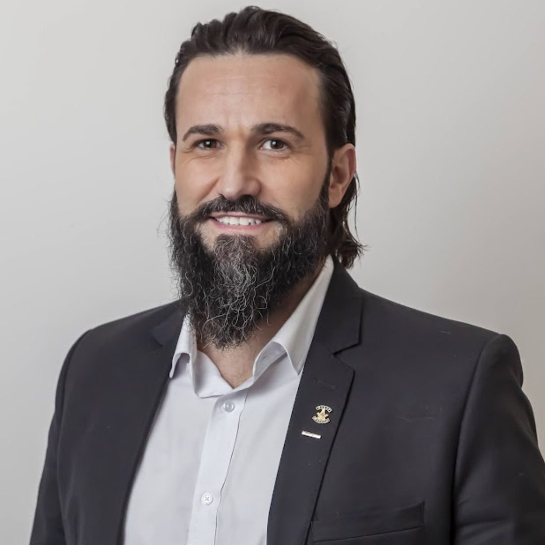 Retrato editorial do Dr. Rodrigo Rocha, psiquiatra e perito judicial do Instituto Alceu Giraldi, com paletó marinho e insígnia oficial de perito