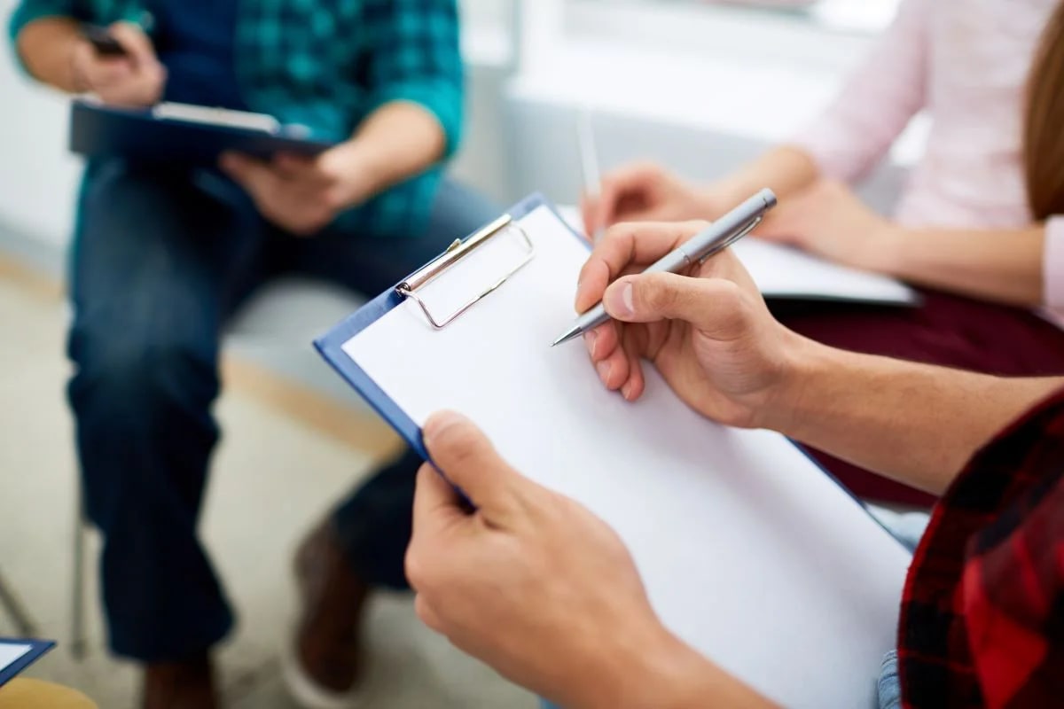 Materiais de avaliação neuropsicológica sobre mesa de consultório com paciente realizando testes