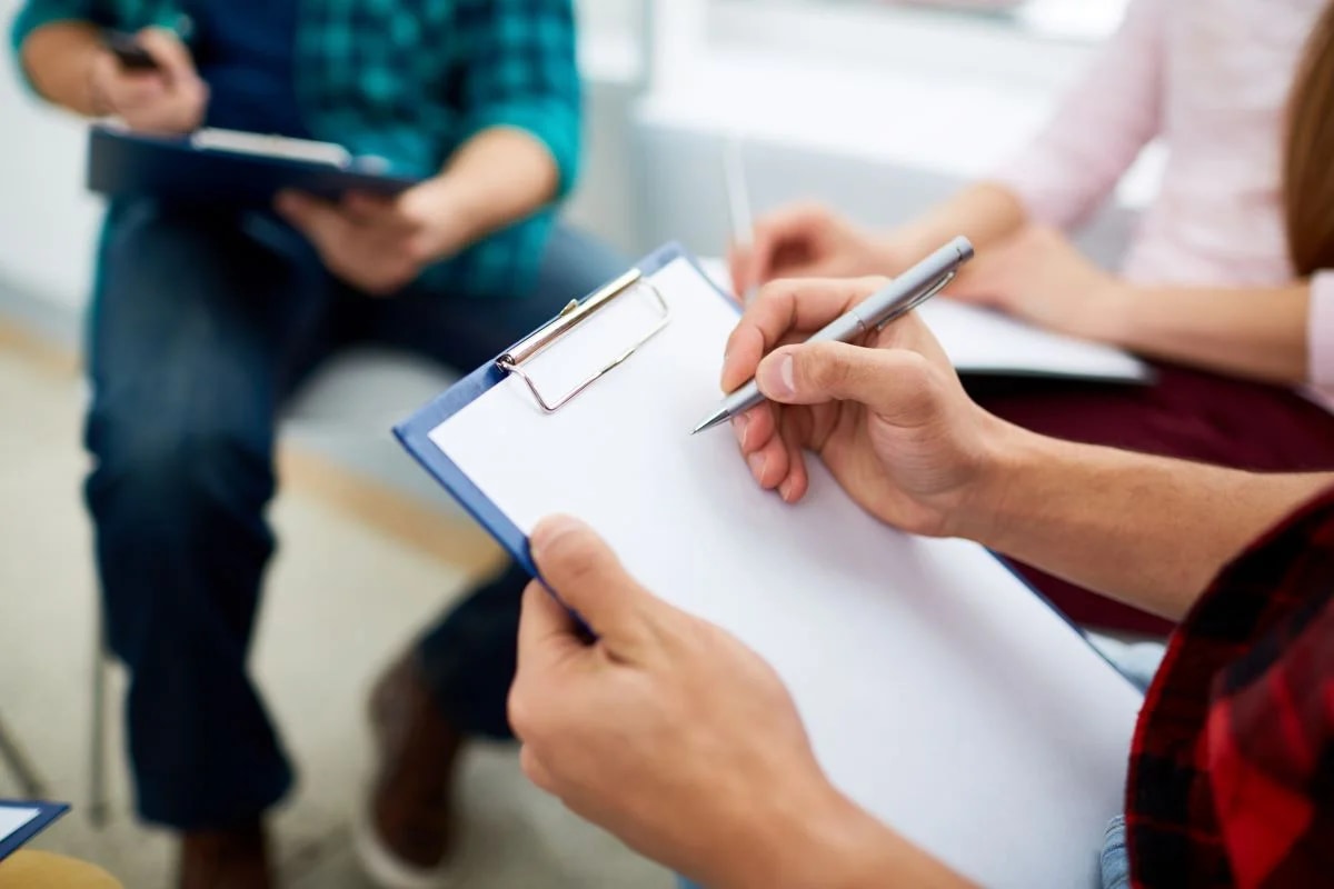 Materiais de avaliação neuropsicológica sobre mesa de consultório com paciente realizando testes