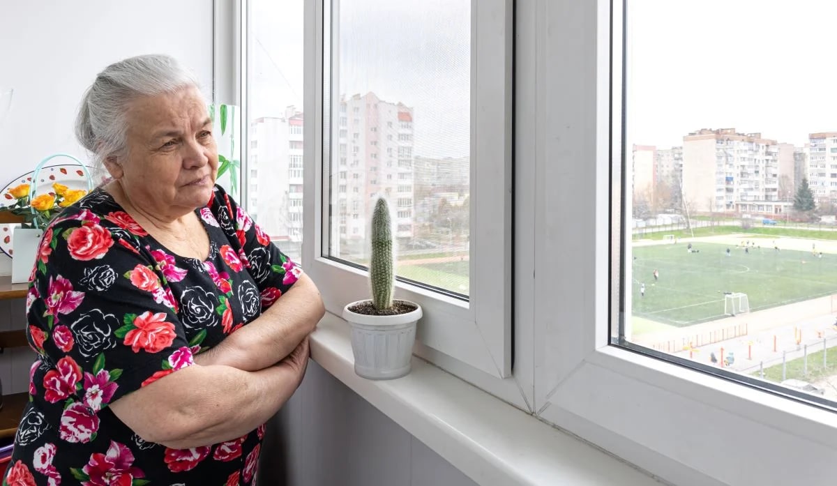 Idoso olhando pela janela em momento melancólico, retrato de depressão na terceira idade