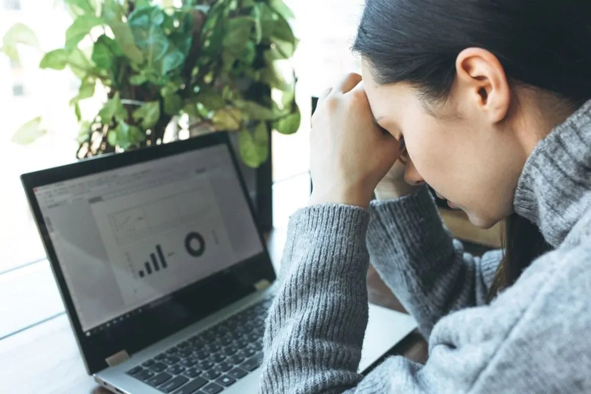 Mulher exausta apoiada em mesa de escritório, retrato de burnout e exaustão mental
