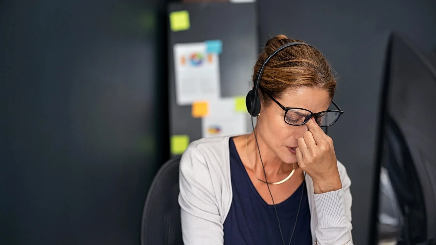 Mulher no trabalho, cansada, com sinais de esgotamento.