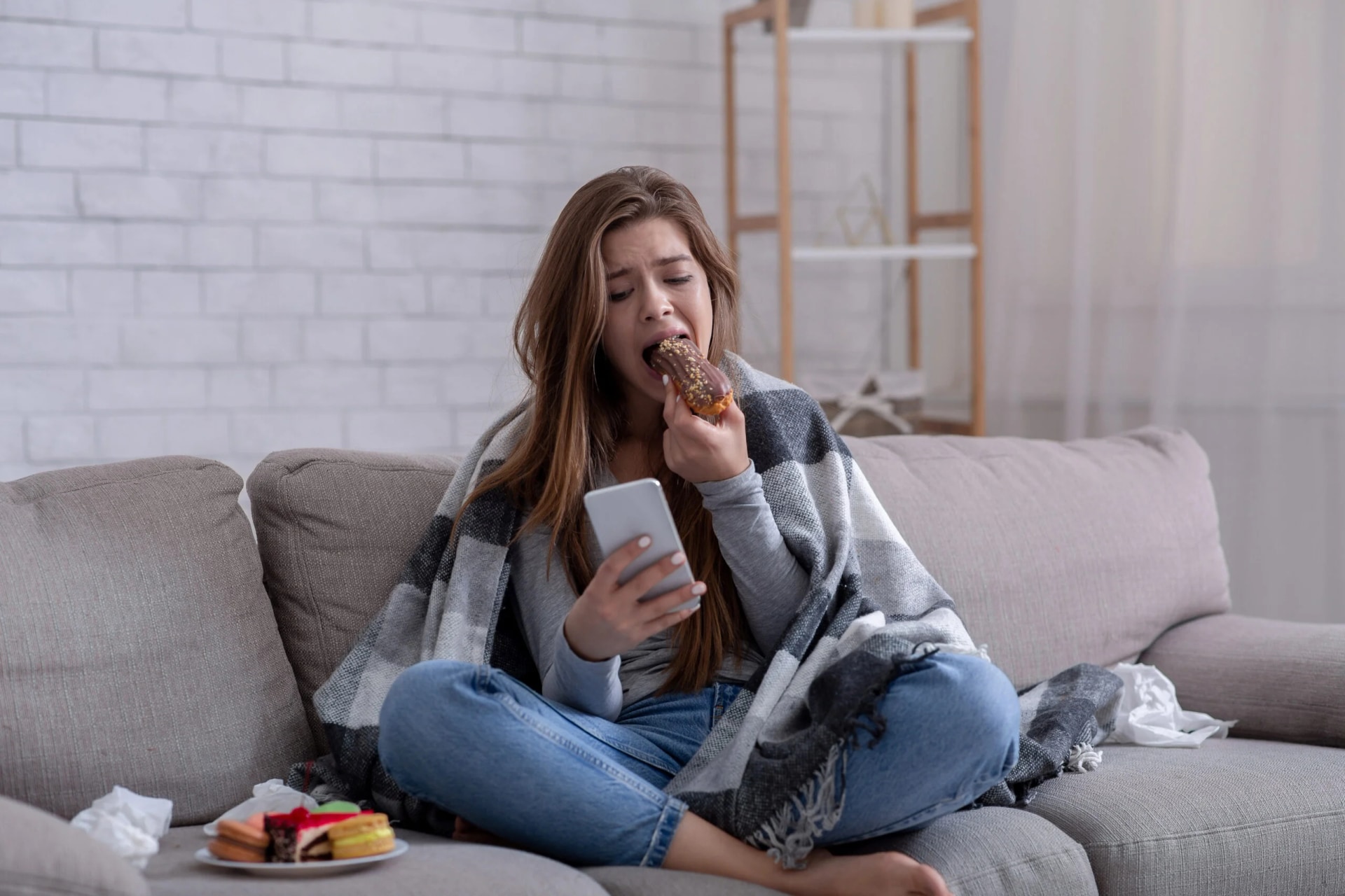 Mulher comendo doce em momento de fome emocional como fuga das emoções difíceis