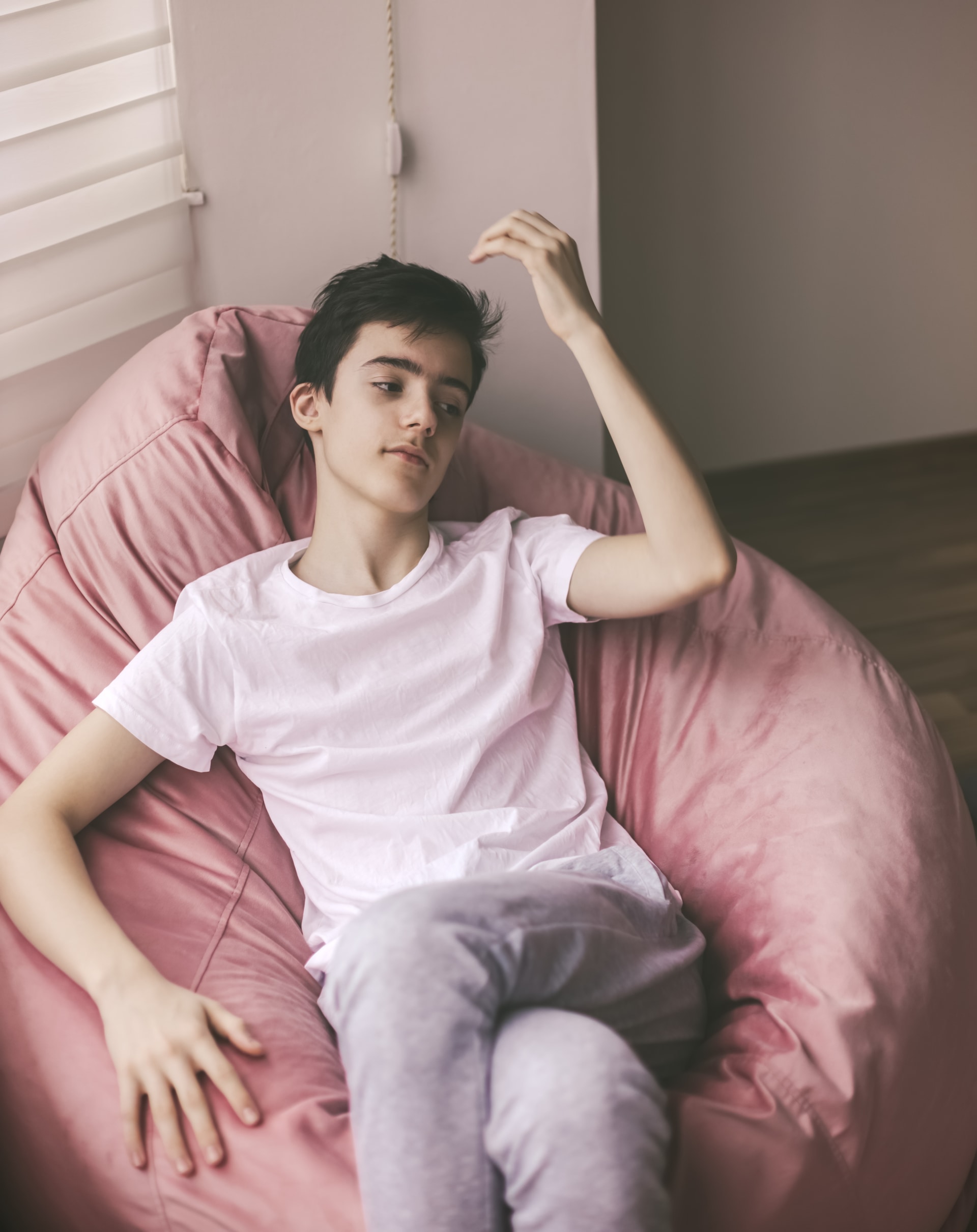Adolescente recostado em poltrona, olhar tranquilo e disperso. Imagem editorial sobre autismo no Instituto Alceu Giraldi.